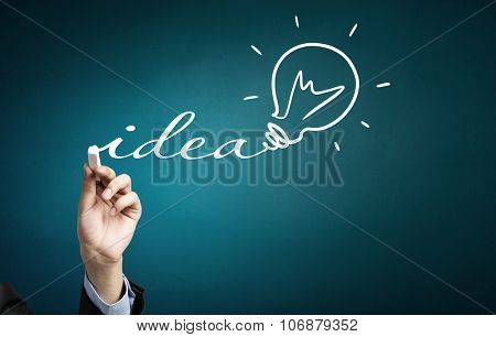 Human hand darwing light bulb as idea concept with chalk