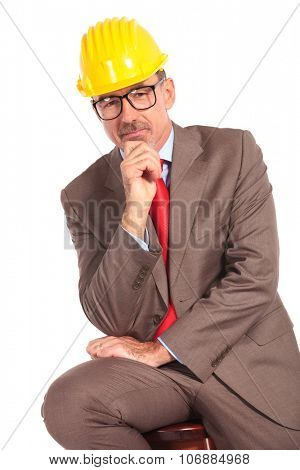 pensive old construcion engineer sitting on chair on white background