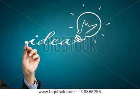 Human hand darwing light bulb as idea concept with chalk