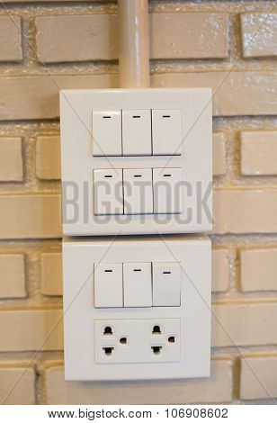 Dimmer Switch And Light Switch On Switchboard.over Brick Wall