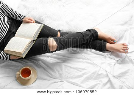 Woman on the bed with old book and cup of coffee, top view point