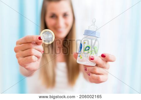 Symbolic picture for family planning, young woman with condom and baby bottle