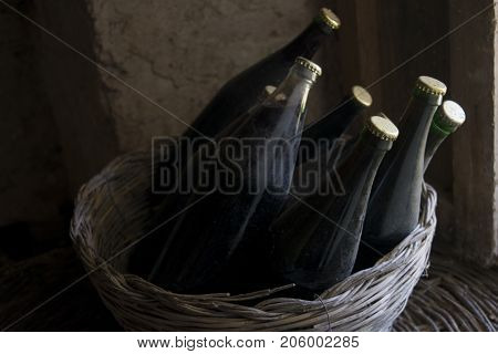 old and dusty botlles of aged red wine in a wicker basket illumined through a window