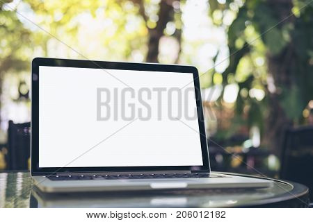 Mockup image of laptop with blank white screen on glass table at outdoor with green nature background