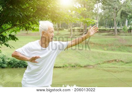 Portrait of healthy white hair Asian senior man practicing martial arts at outdoor park in morning.