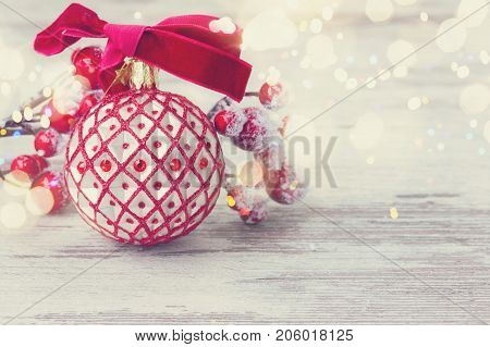 red an white christmas - ball and twig with frosted berries clos eup on aged wooden background, retro toned