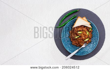 Braised eggplant in tomato and chocolate sauce with green chili peppers. Slate round background. Selective focus. Copy space. Marble background.