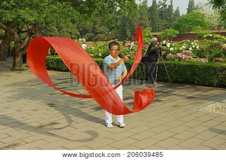 BEIJING, CHINA - MAY 01, 2009: Unidentified lady practices traditional gymnastics with red ribbon in Jingshan Park in Beijing, China.