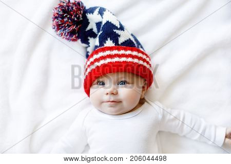 Cute adorable baby child with Christmas winter cap on white background. Happy baby girl or boy smiling and looking at the camera. Close-up for xmas holiday and family concept.