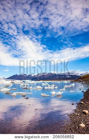 Clouds reflected in the water of lagoon. The ice floes and cirrocumulus clouds of lagoon Jokulsarlon, Iceland. The concept of northern extreme tourism