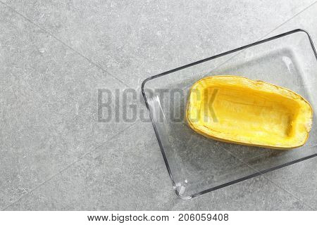 Baking dish with half of baked spaghetti squash on table