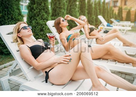 Three girls relax and sunbathig on deck chairs