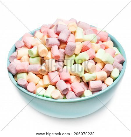 Fluffy multi colourful marshmallows in blue round bowl isolated on white background with copy space. Various colours marshmellows close up.