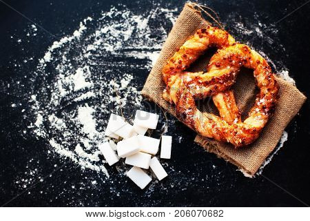 Delicious Fresh Bavarian pretzel on dark background with flour. Sweet pretzels with powdered sugar macro. Beautiful delicious puff pastry
