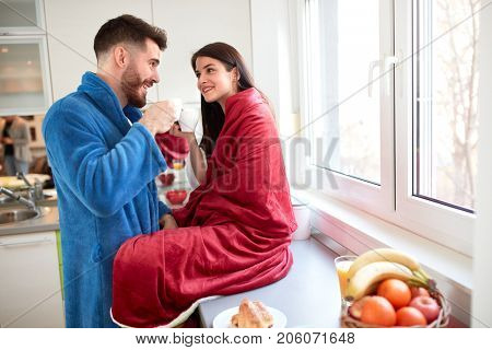 Beautiful couple in love drinking coffee in kitchen