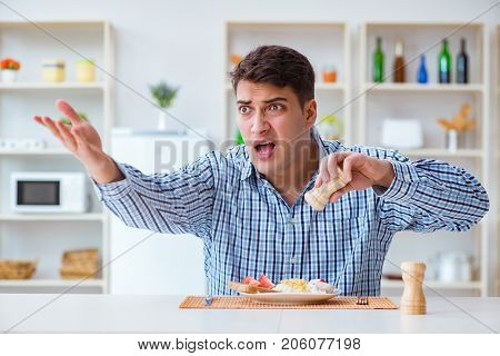 Young husband eating tasteless food at home for lunch