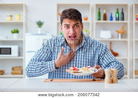 Young husband eating tasteless food at home for lunch