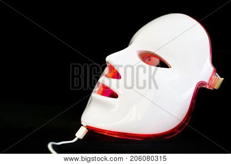 Light rejuvenating mask for facial skin therapy on black background
