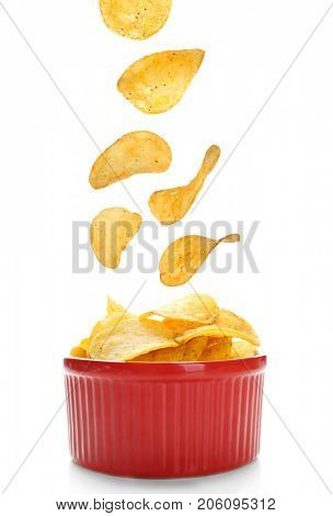 Tasty potato chips falling into bowl on white background