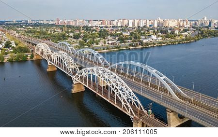 Aerial top view of automobile and railroad Darnitsky bridge across Dnieper river from above, Kiev (Kyiv) city skyline, Ukraine