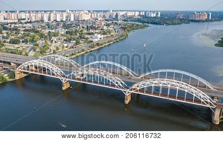 Aerial top view of automobile and railroad Darnitsky bridge across Dnieper river from above, Kiev (Kyiv) city skyline, Ukraine