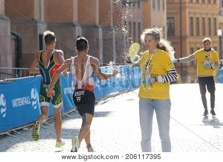STOCKHOLM - AUG 26 2017: Official giving water bottle to running triathlete Bergere (FRA) in the Men's ITU World Triathlon series event August 26 2017 in Stockholm Sweden
