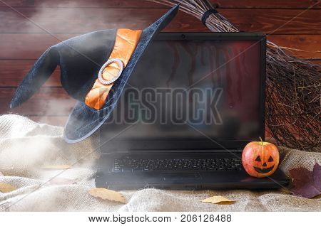 The Concept Of Halloween: A Laptop, A Witch Hat And A Broom, Free Space For Your Advertising.