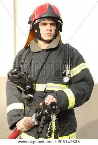half-height portrait of fireman holds and adjust nozzle and fire hose spraying high pressure water, no jet