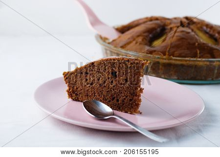 Slice of pear pie on pink plate with whole baked pie in background