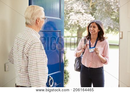 Senior man opens front door to young woman making home visit