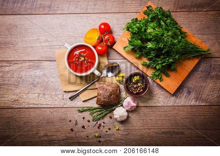 Red ukrainian borsch with sour, garlic, parsley, spices and a lot of dill and parsley on a wooden background. Copy space. Close-up of appetitzing dish. Food concept.