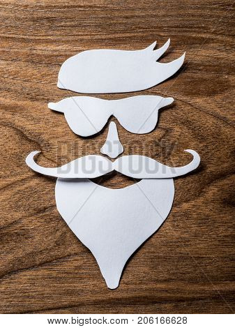 Hipster's definicial facial look cut from paper on the wooden background.