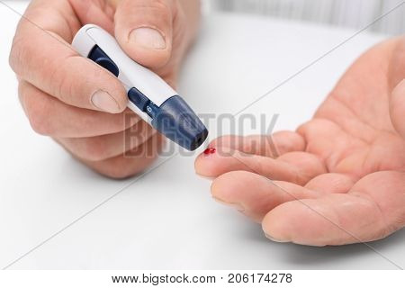 Man taking blood sample with lancet pen indoors