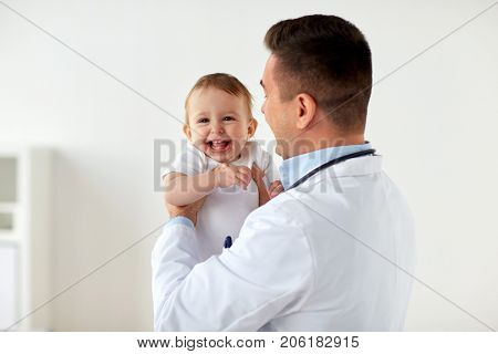 medicine, healtcare, pediatry and people concept - happy doctor or pediatrician holding baby on medical exam at clinic