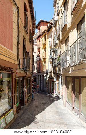 TOLEDO,SPAIN - AUGUST 8,2017 : Typical narrow street with restaurants and handicraft shops on the medieval city of Toledo in Spain