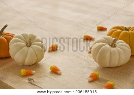 Mini pumpkins with candy corn scattered around.