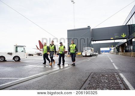 Full Length Of Workers Walking Together On Runway
