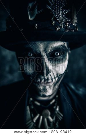 Close-up portrait of a man with a skull makeup dressed in a tail-coat and a top-hat. Baron Saturday. Baron Samedi. Dia de los muertos. Day of The Dead. Halloween.