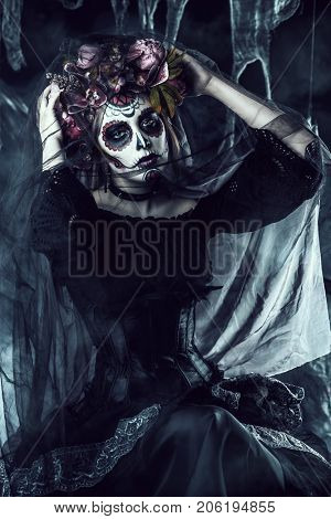 Calavera Catrina in black dress over dark background. Sugar skull makeup. Dia de los muertos. Day of The Dead. Halloween.  