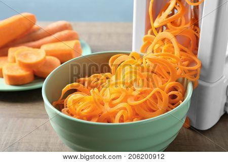 Spiral vegetable slicer with carrot spaghetti on table