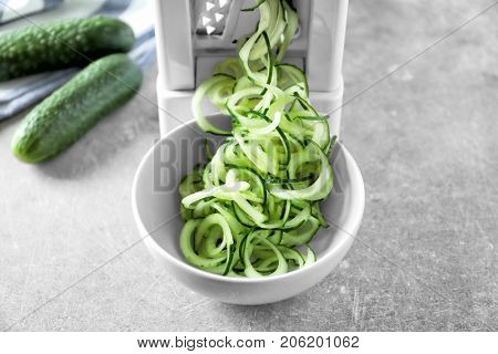 Spiral vegetable slicer with cucumber spaghetti on table