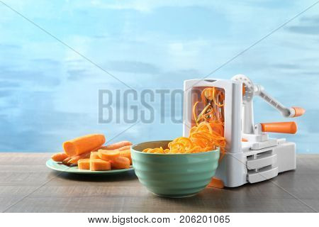 Spiral vegetable slicer with carrot spaghetti on table