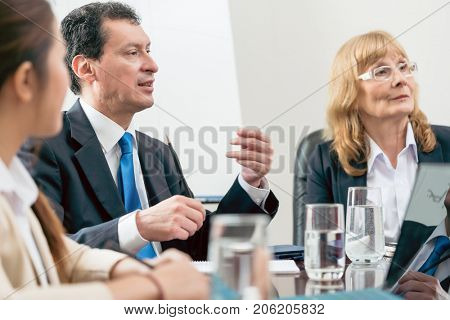 Side view of an expert businessman sharing his view about the development of an important project during a decision-making meeting in the conference room