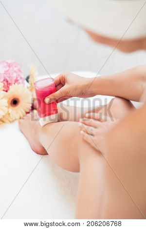 Close-up of the hand of a young woman using a modern recharchable roll-on waxer for removing hair from her legs at home