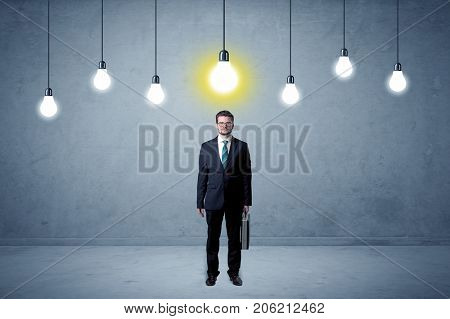 Handsome businessman in an empty space with bulbs above and uninspired face