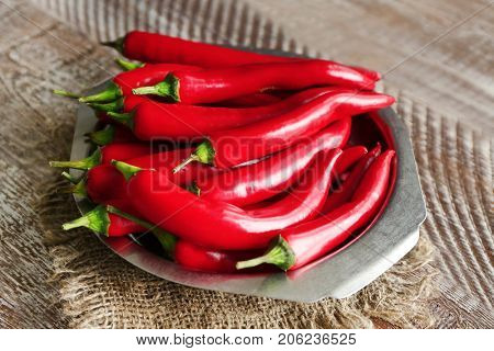 Plate with red chili peppers on wooden table