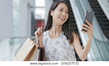 Woman making video call and holding shopping bag
