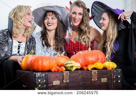 Three young and beautiful women wearing funny party costumes while acting as witches joining their malicious forces at Halloween