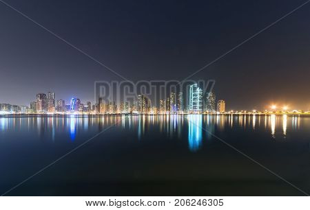 An illuminated Sharjah corniche skyline in the night.