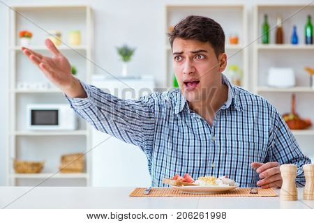 Young husband eating tasteless food at home for lunch